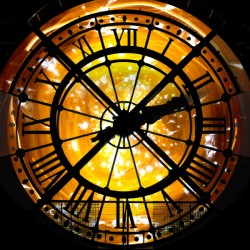 Close-up of a large clock face with Roman numerals illuminated by warm golden light.