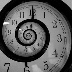A black and white clock face with a spiral effect distorting the numbers inward.
