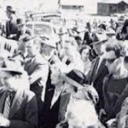 Black and white photo of a large crowd of people gathered outdoors, many wearing hats and coats.