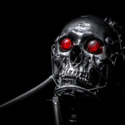 A metallic skull with glowing red eyes and wires attached, set against a black background.