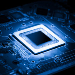 Close-up of a glowing microchip on a dark blue circuit board, highlighting intricate electronic components.