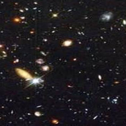 A deep space image showing numerous galaxies and stars scattered across the dark universe.