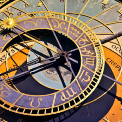 Close-up of an ornate astronomical clock with zodiac signs and intricate golden details.
