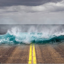 A surreal image of ocean waves crashing onto a road with yellow dividing lines under a cloudy sky.