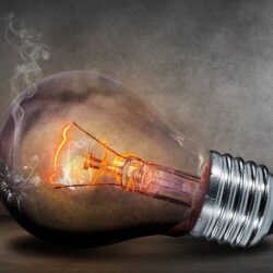 A light bulb with fire coming out of it.